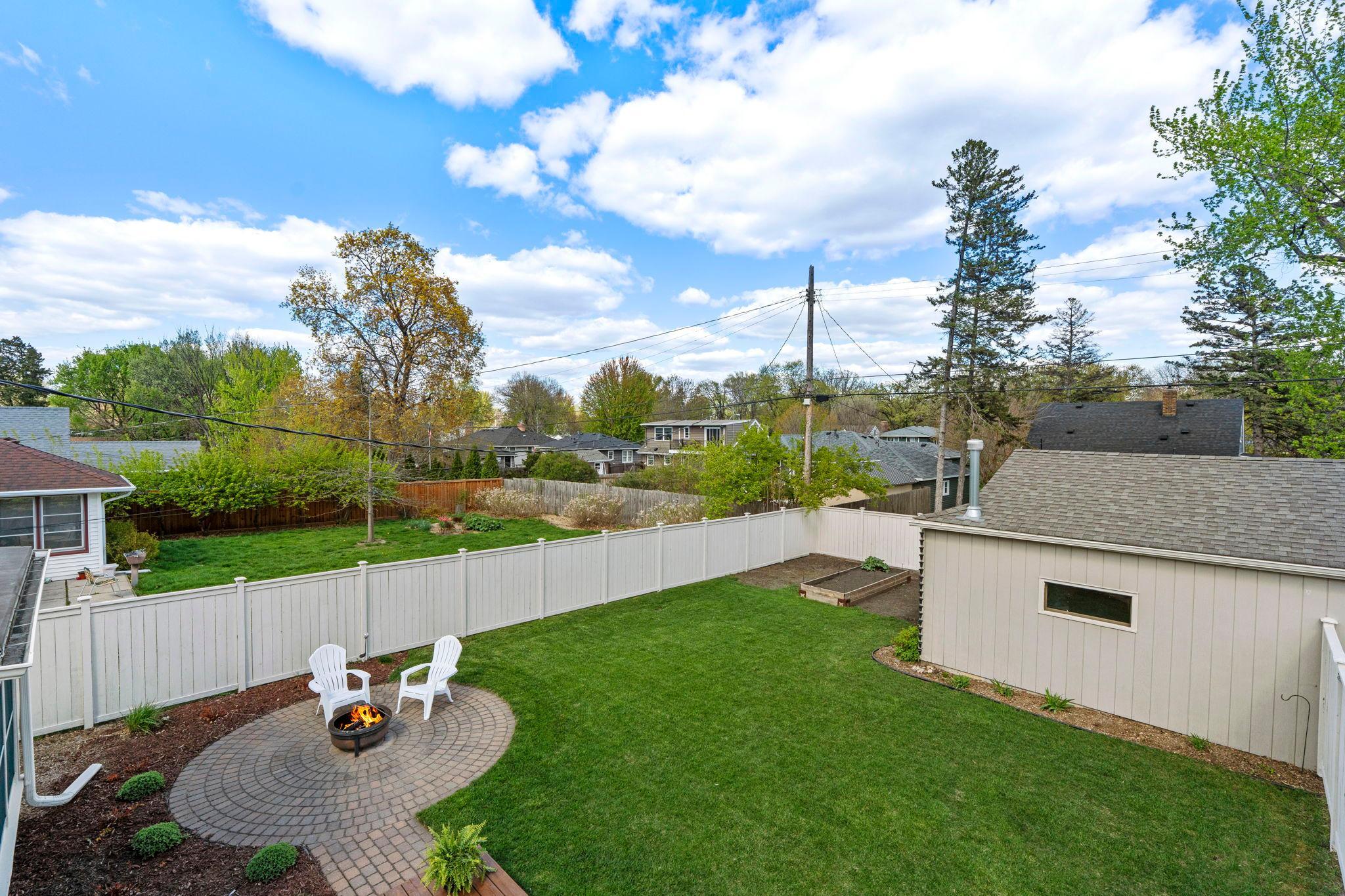 Offering a fully fenced yard for privacy, along with a garden bed, a spacious deck, access to the three-season porch, and a patio area ideal for a fire pit.
