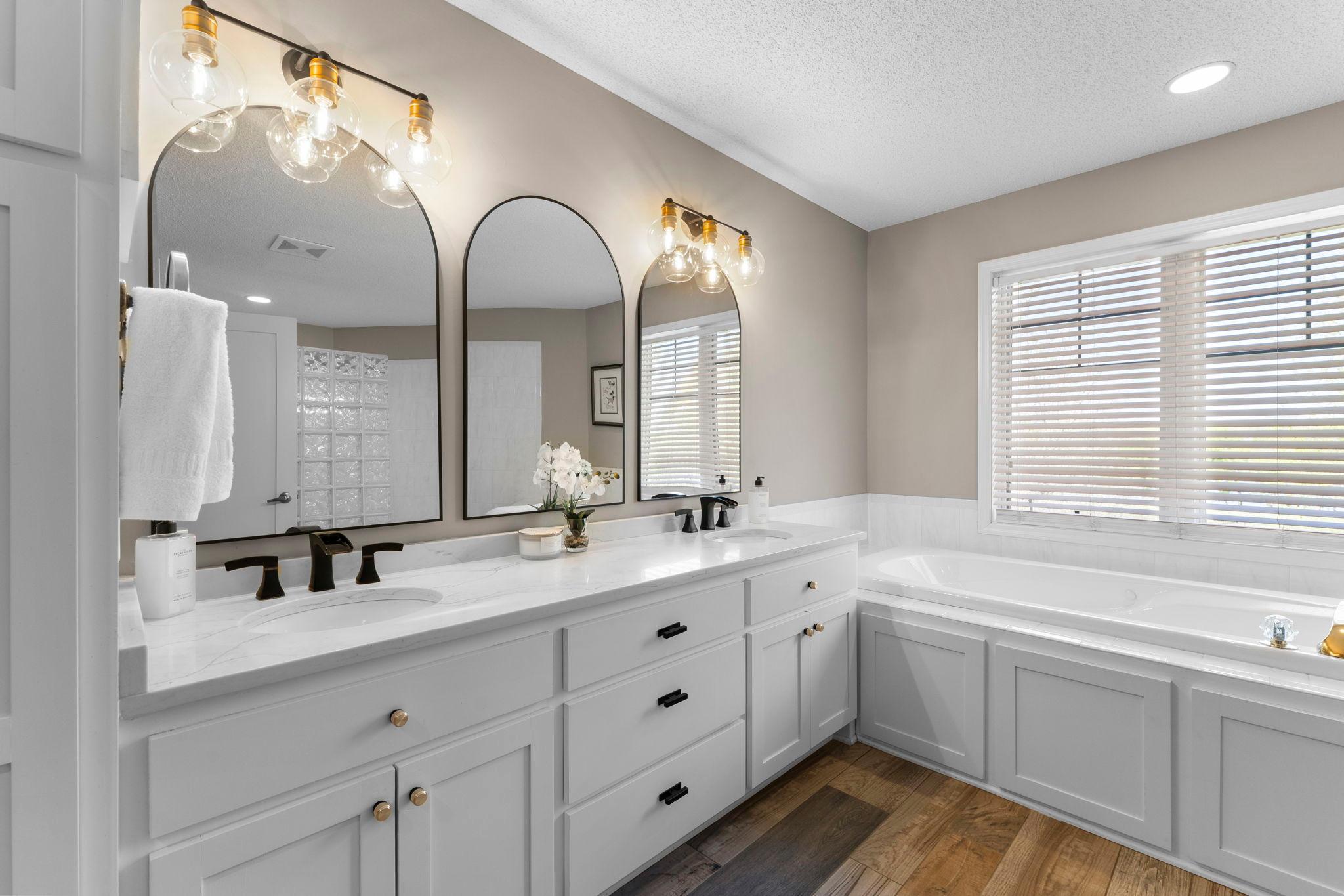 The private ensuite features updated quartz countertops (2022), dual vanities, luxury flooring, a spa-like jetted tub, a large tiled walk-in shower, and a separate water closet.