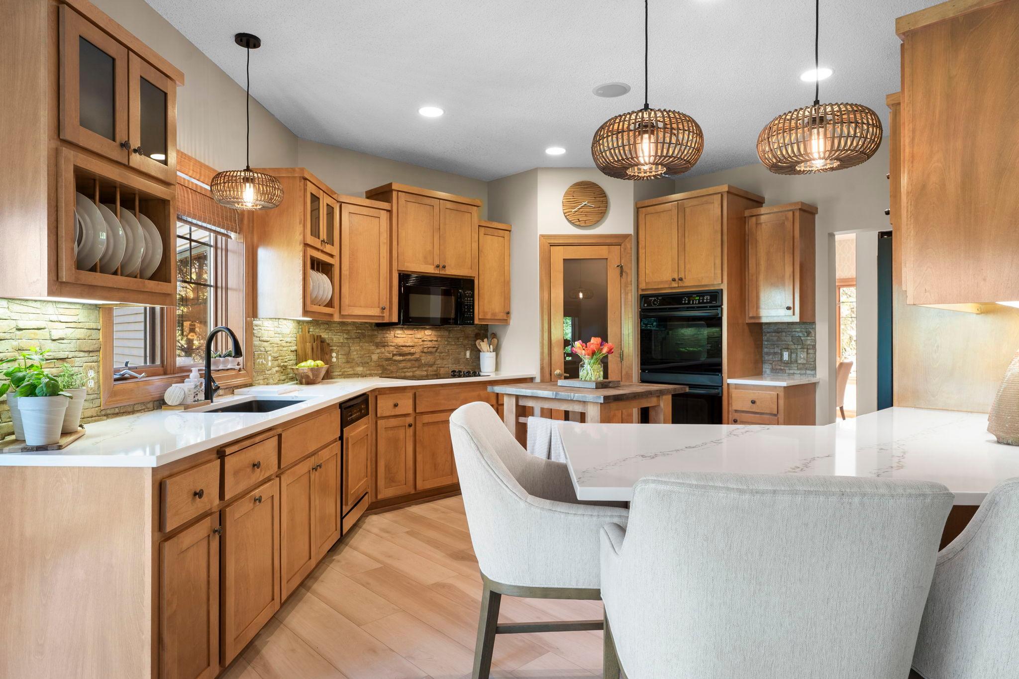 The chef’s kitchen is designed to impress, featuring timeless wood cabinetry, updated quartz countertops (2022), and a spacious breakfast bar with stylish pendant lighting.