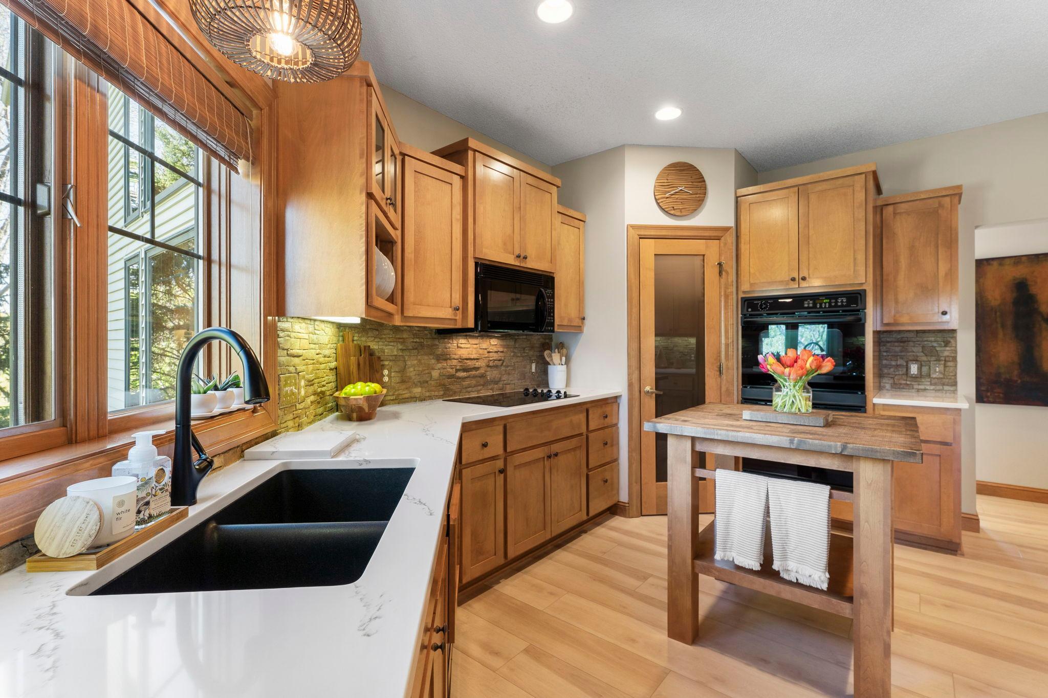 Additional highlights include a stone backsplash, updated sink and faucet, and a window overlooking peaceful backyard views.