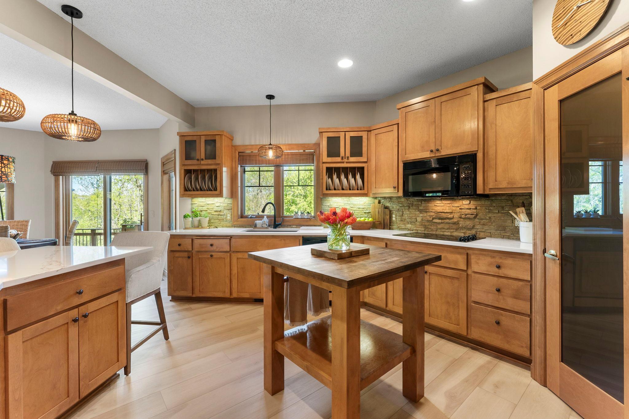 Sleek black appliances include a double oven, electric cooktop along with a cabinet-covered refrigerator and dishwasher.