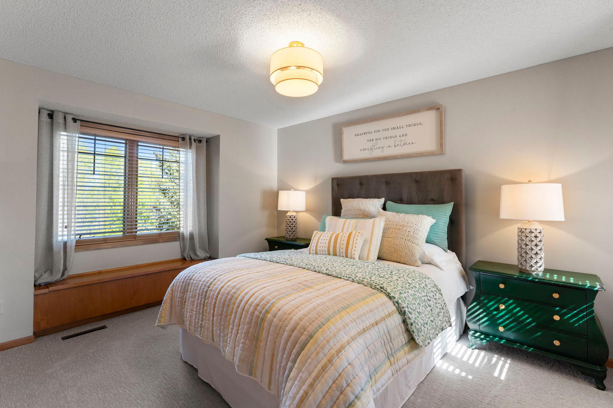 The third upper-level bedroom offers carpeting, a built-in storage bench, and generous closet space.