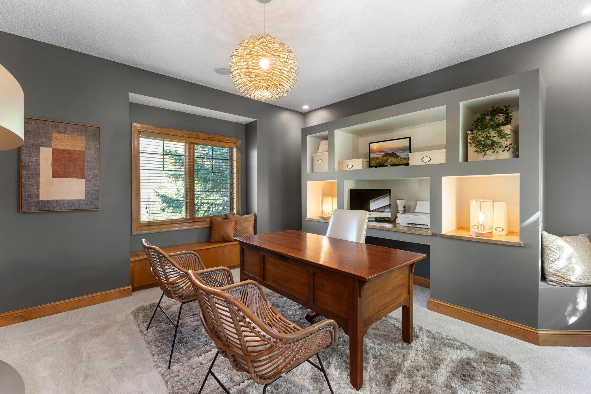 This versatile room features carpeting, built-in shelving, front and rear-facing windows, a stylish hanging light fixture, and a built-in bench with storage overlooking the backyard.