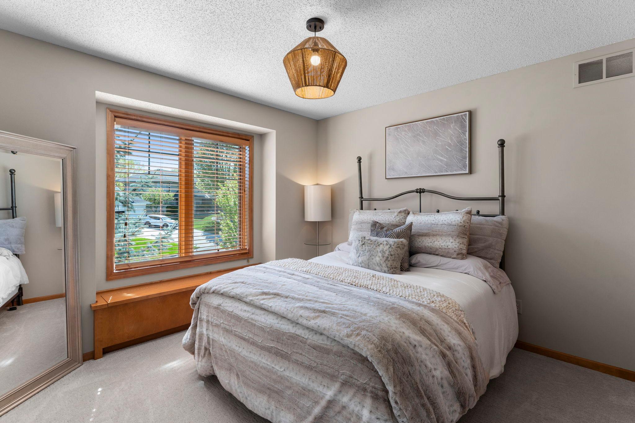 Bedroom two features carpeting, a built-in window bench with storage, and ample closet space with custom built-ins.