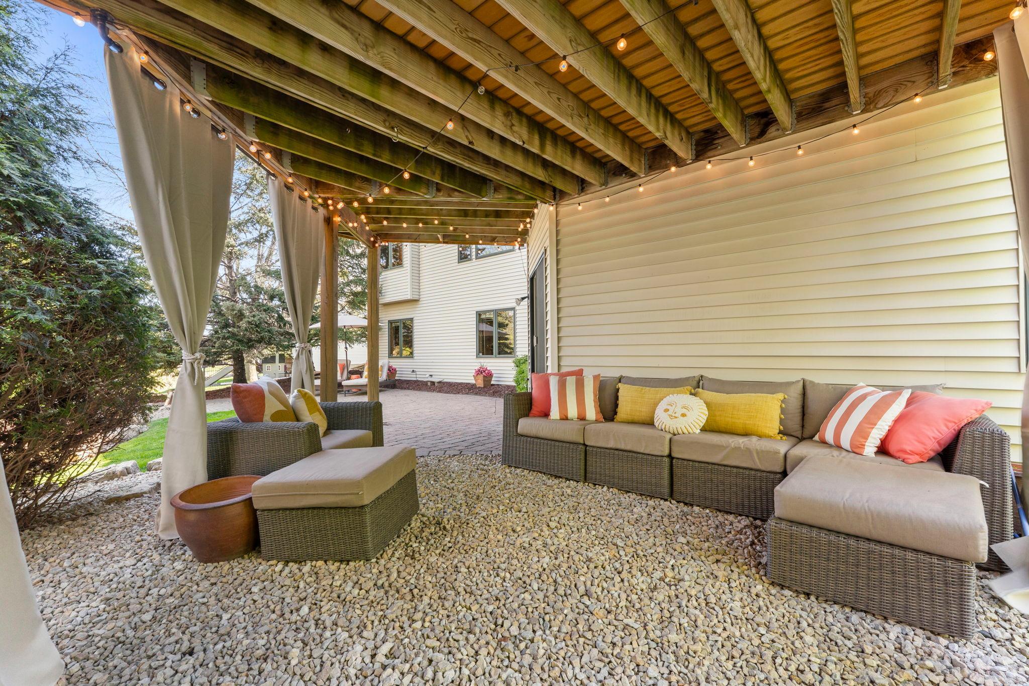 Under the deck is a rock-scaped area with string lighting, perfect for an additional outdoor seating space.