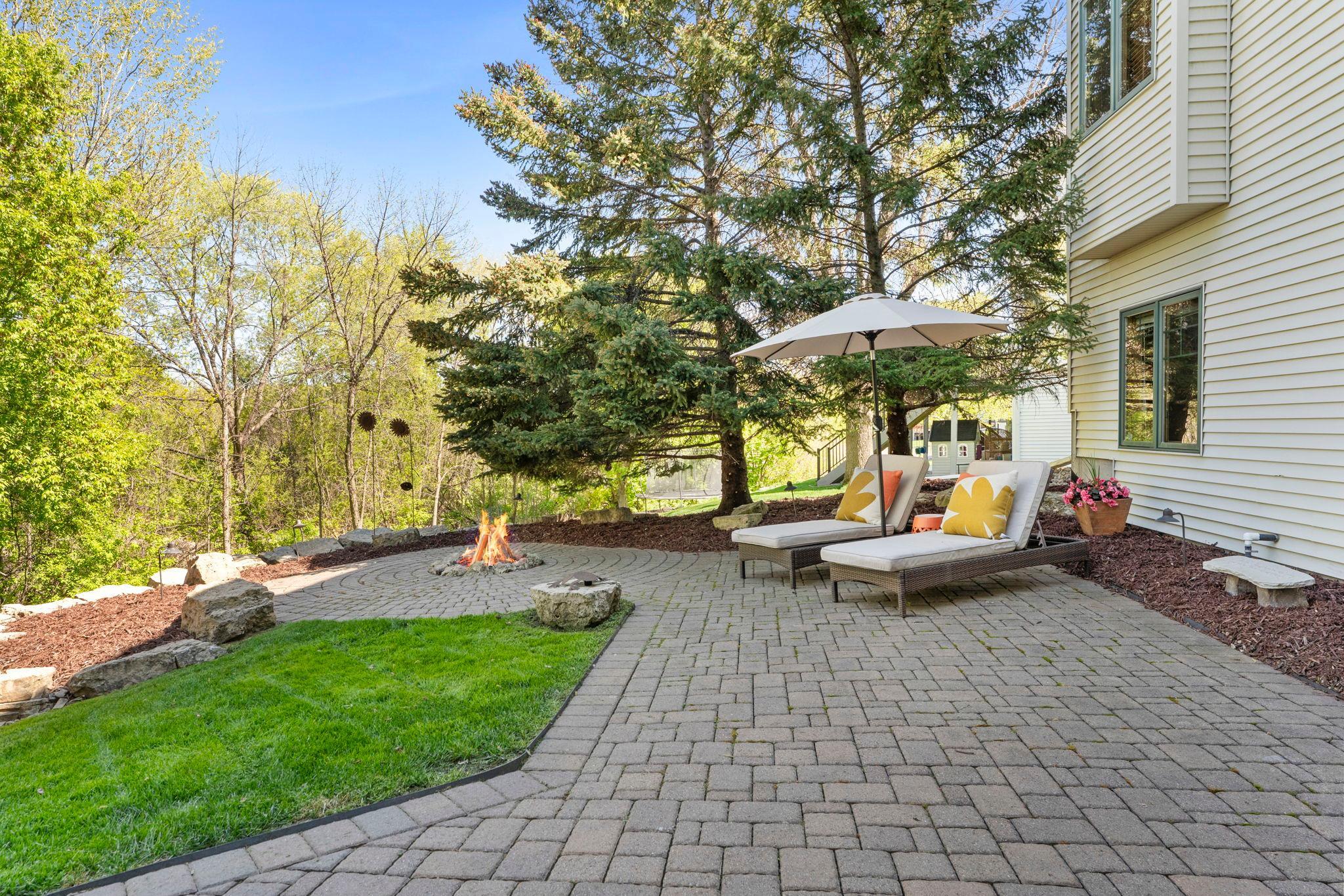 Outdoor living shines with a paver patio, updated landscaping, string lighting, and a firepit area.