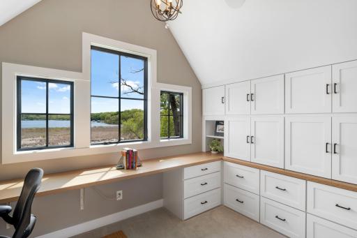 The second upper-level wing features a dedicated office space with vaulted ceilings, custom built-in cabinetry, and a spacious L-shaped desk.
