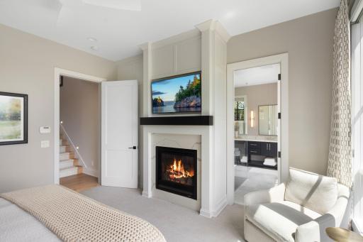 A closer look at the cozy gas fireplace and access to the private ensuite bathroom.