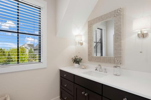 Just steps away from the bedroom is a full bathroom featuring a single vanity and a tub and shower combination with a tile surround.