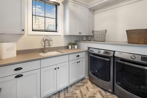 The laundry room offers abundant cabinetry and counter space, along with front-loading Maytag washer and dryer.