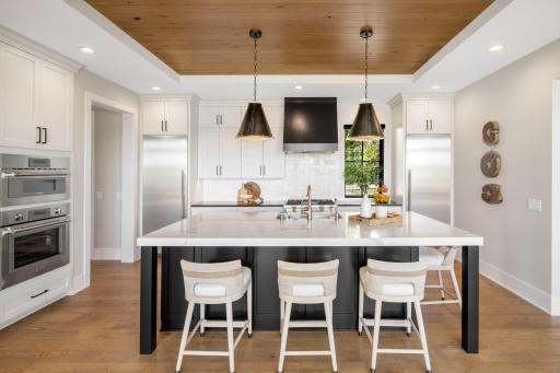 A coved ceiling accented with white oak paneling adds architectural interest, while an 8x6 walk-in pantry with a pocket door provides exceptional storage.