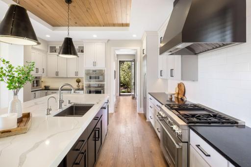 Custom white and black cabinetry with soft-close doors, under-cabinet lighting, and a stylish tile backsplash add both beauty and function.
