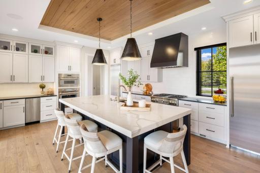 The kitchen is truly a chefâs dream, showcasing stunning quartz countertops, an expansive center island with distinctive pendant lighting, and breakfast bar seating.