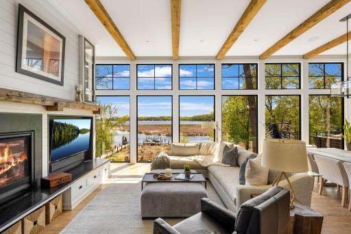 The living room offers a cozy gas-burning fireplace, built-in storage, a charming wood mantel, and a floor-to-ceiling shiplap surround with upper glass cabinets perfect for displayâall positioned to take full advantage of the incredible outdoor view.