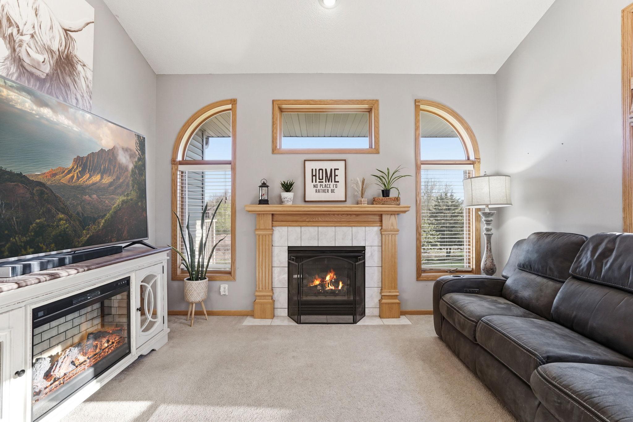 Warm, welcoming living room featuring ample lighting and a gas fireplace.
