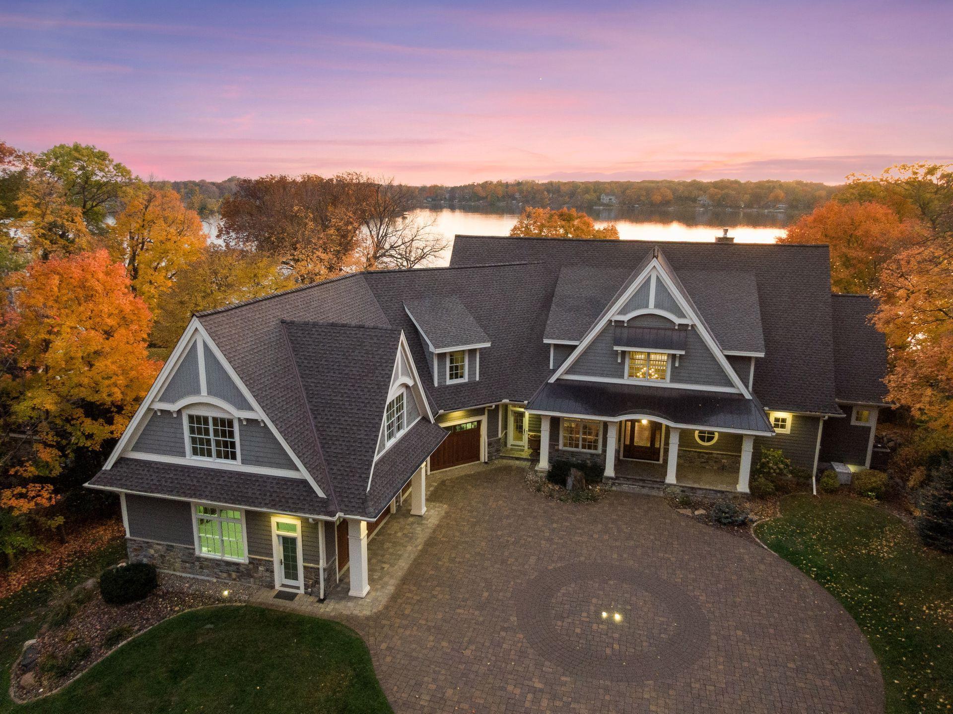 Elevated perspective showcasing the home's impressive scale, circular drive, and picturesque setting on Lake Minnetonka