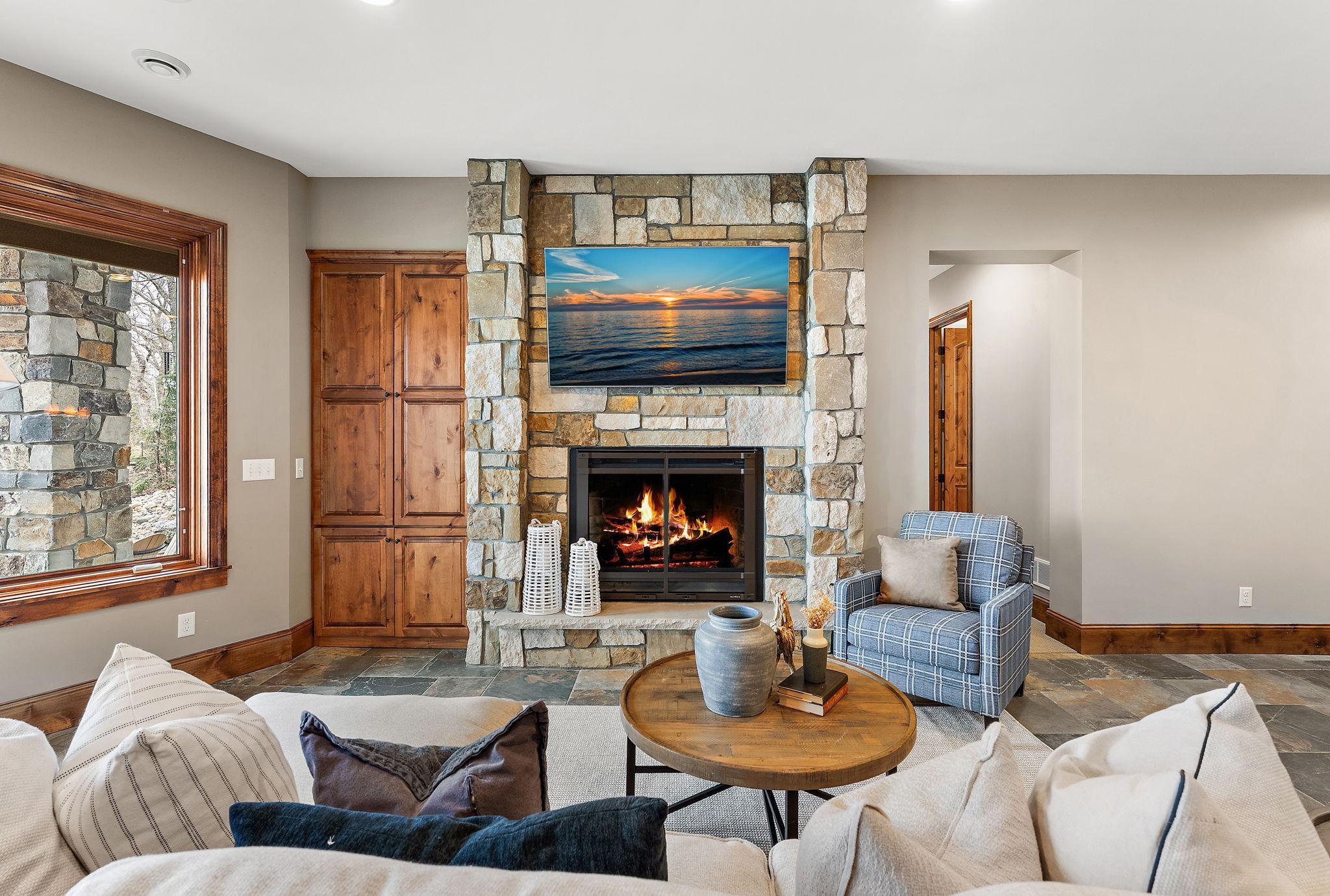Cozy lower-level living area enhanced by in-floor heat and a stone gas fireplace