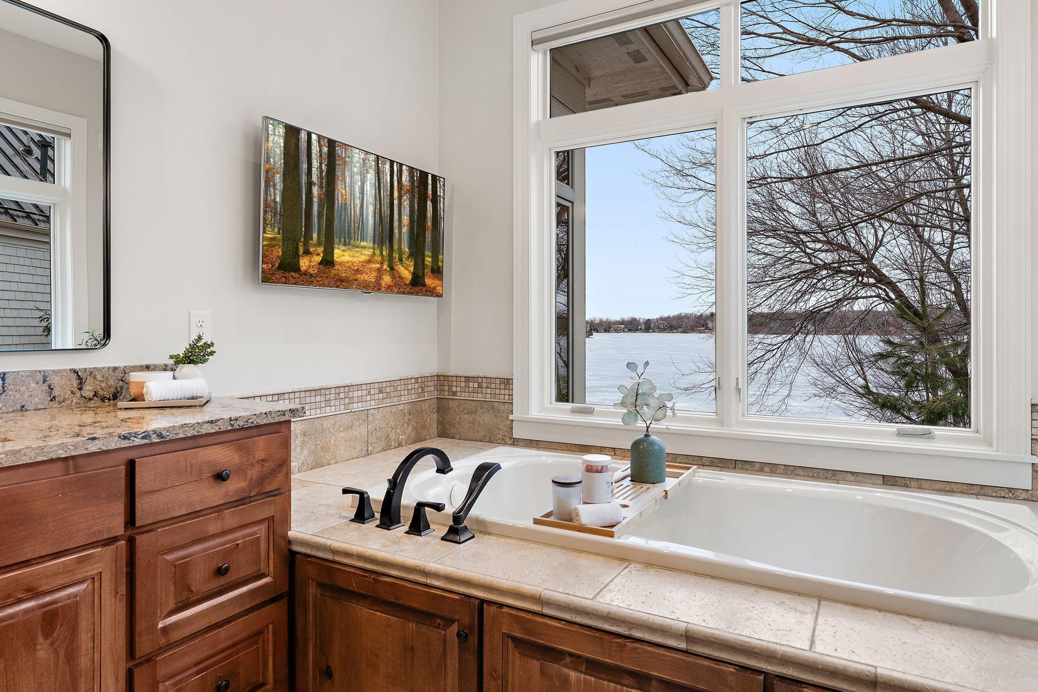 Spa-inspired primary bath with jetted tub and tranquil lake views (bath #1)