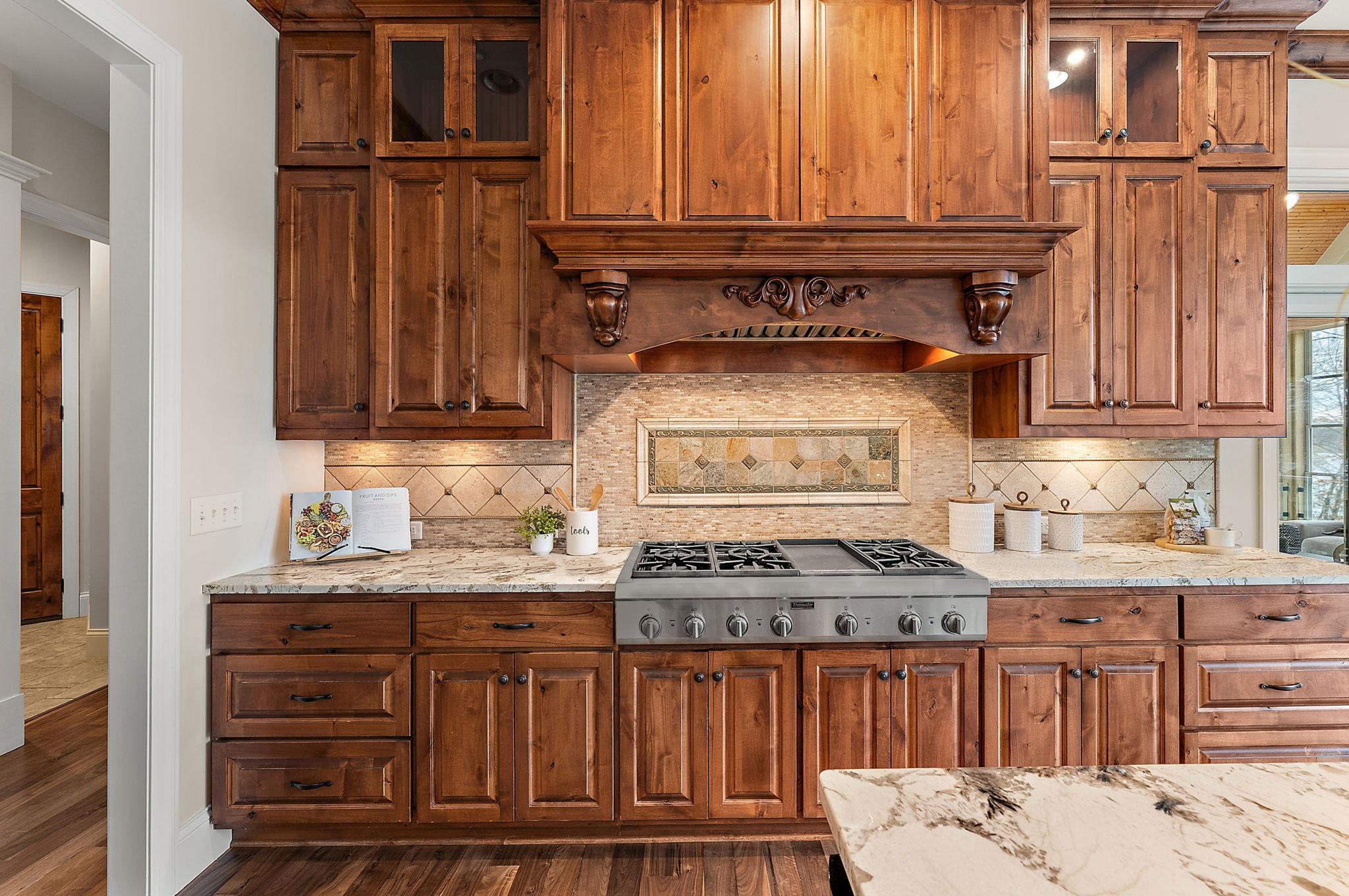 Custom cabinetry and a statement range wall with decorative hood and stone backsplash