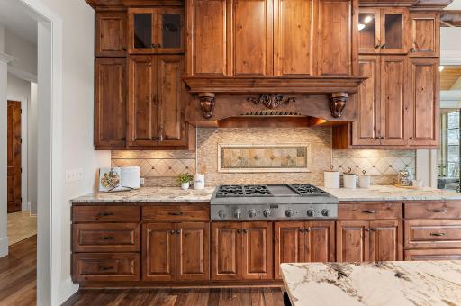 Custom cabinetry and a statement range wall with decorative hood and stone backsplash