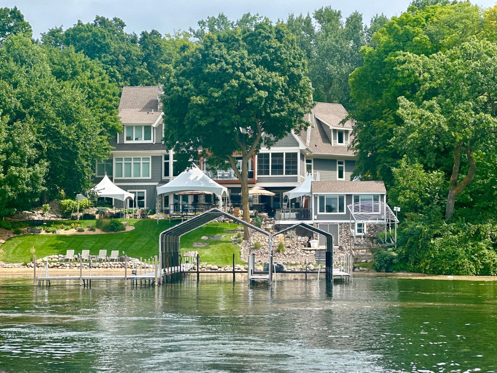 Summer photo highlighting the 98-foot dock with canopies and a flat lawn space ideal for large gatherings and tented events