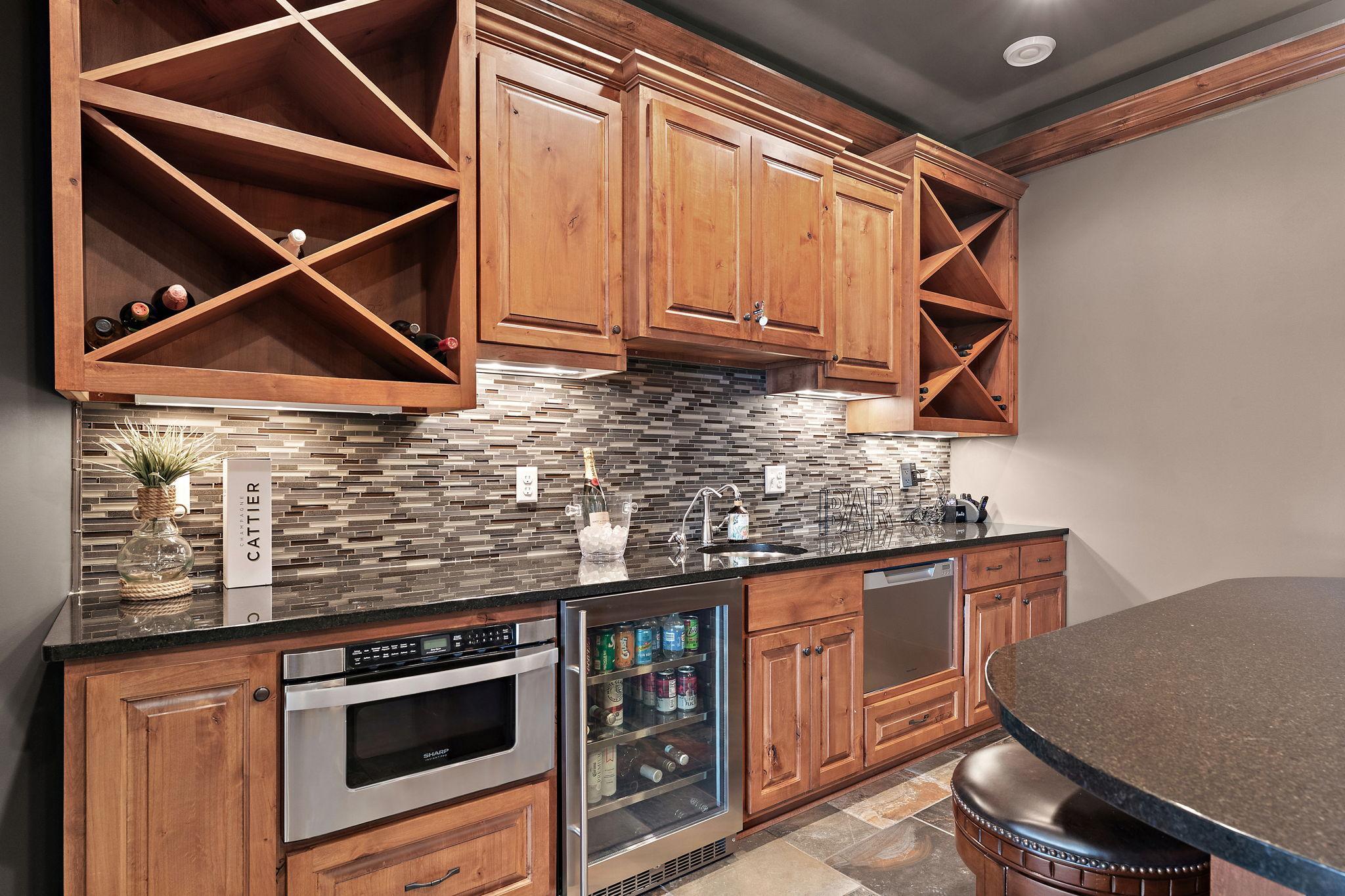 Sophisticated wet bar in the theater room complete with beverage fridge, wine storage, microwave, and dishwasher