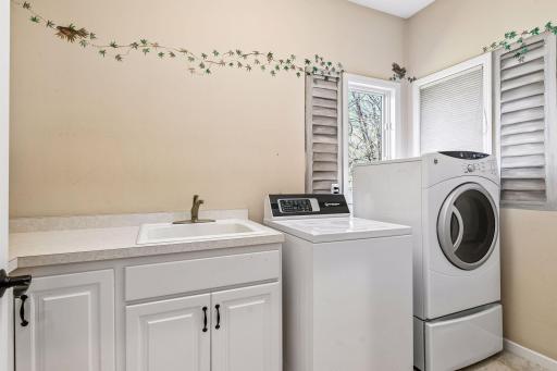 Main floor laundry room with sink, counters and so many cabinets for storage