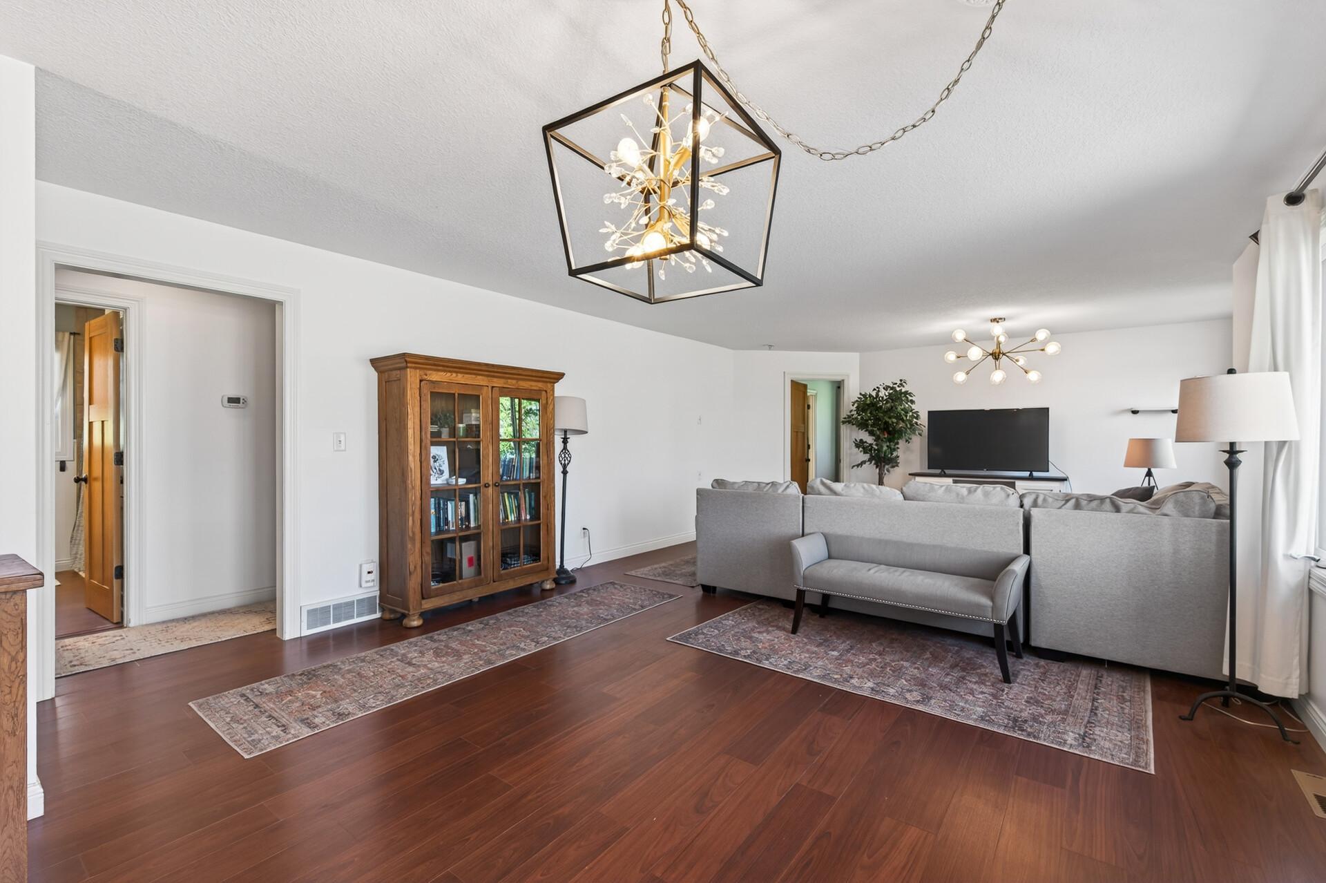 Open concept main level living with dark updated laminate flooring, light neutral walls, stylish light fixtures and views towards the lake.
