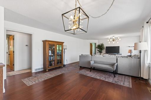 Open concept main level living with dark updated laminate flooring, light neutral walls, stylish light fixtures and views towards the lake.