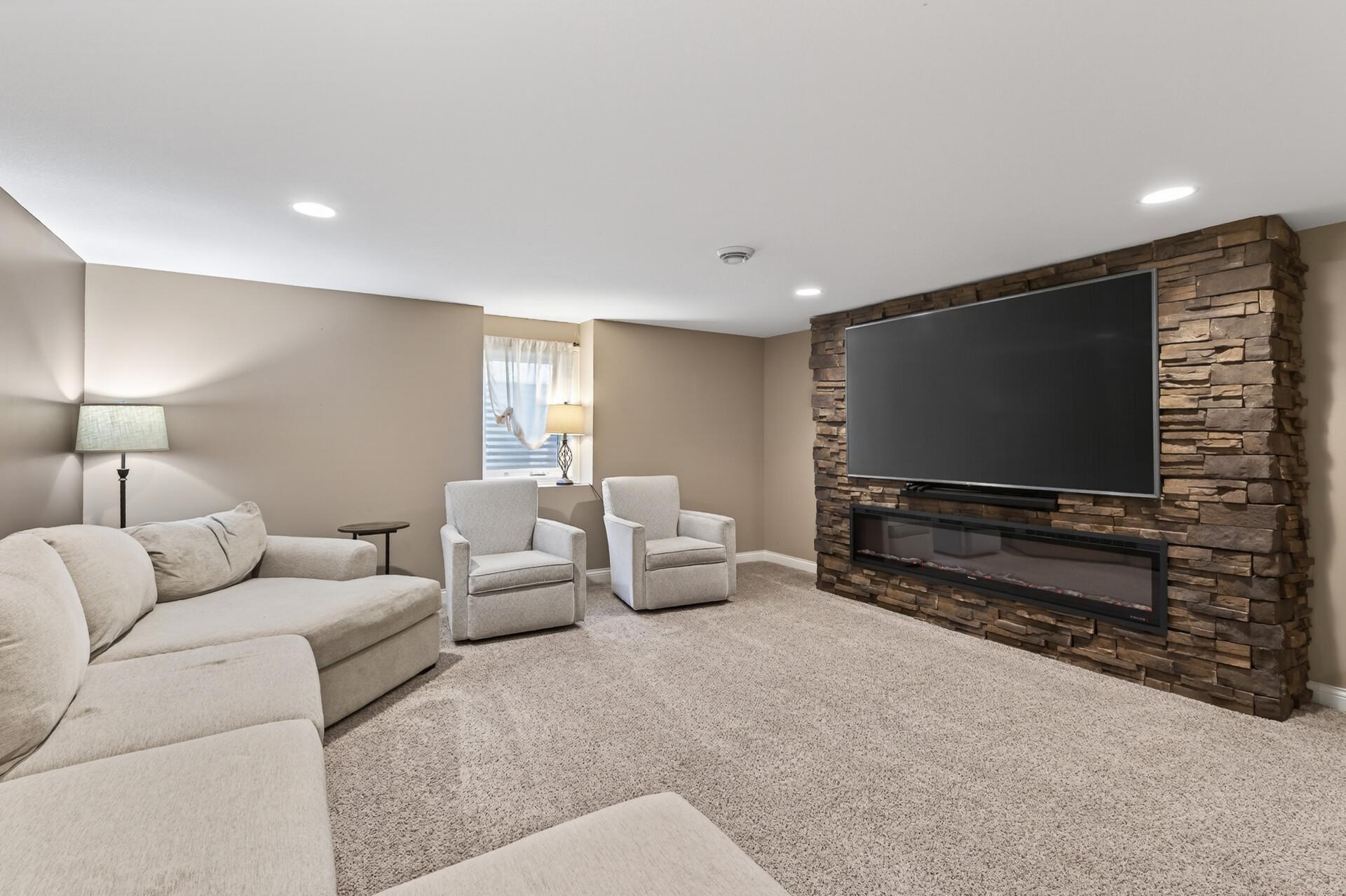 Natural light and fresh finishes in this amazing lower level family room, complete with cozy electric fireplace and large screen mounted TV (stays with the house!).