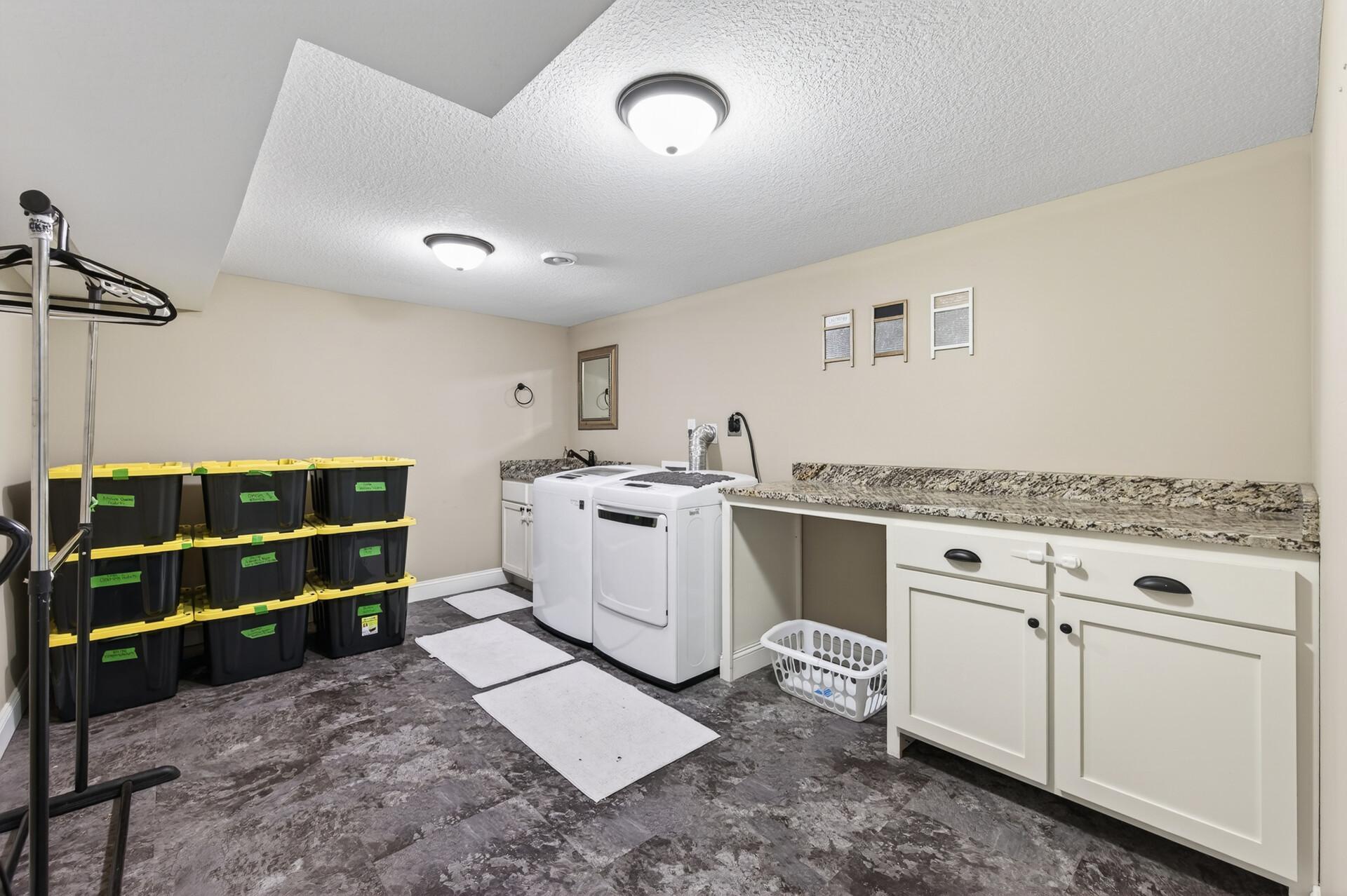 You may actually enjoy doing laundry in this bright and enormous lower level laundry room with plenty of folding area, wash sink and cabinet storage!