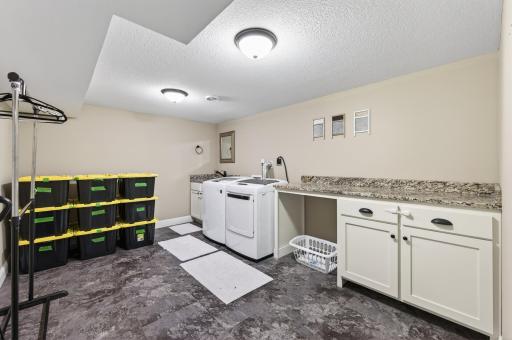 You may actually enjoy doing laundry in this bright and enormous lower level laundry room with plenty of folding area, wash sink and cabinet storage!
