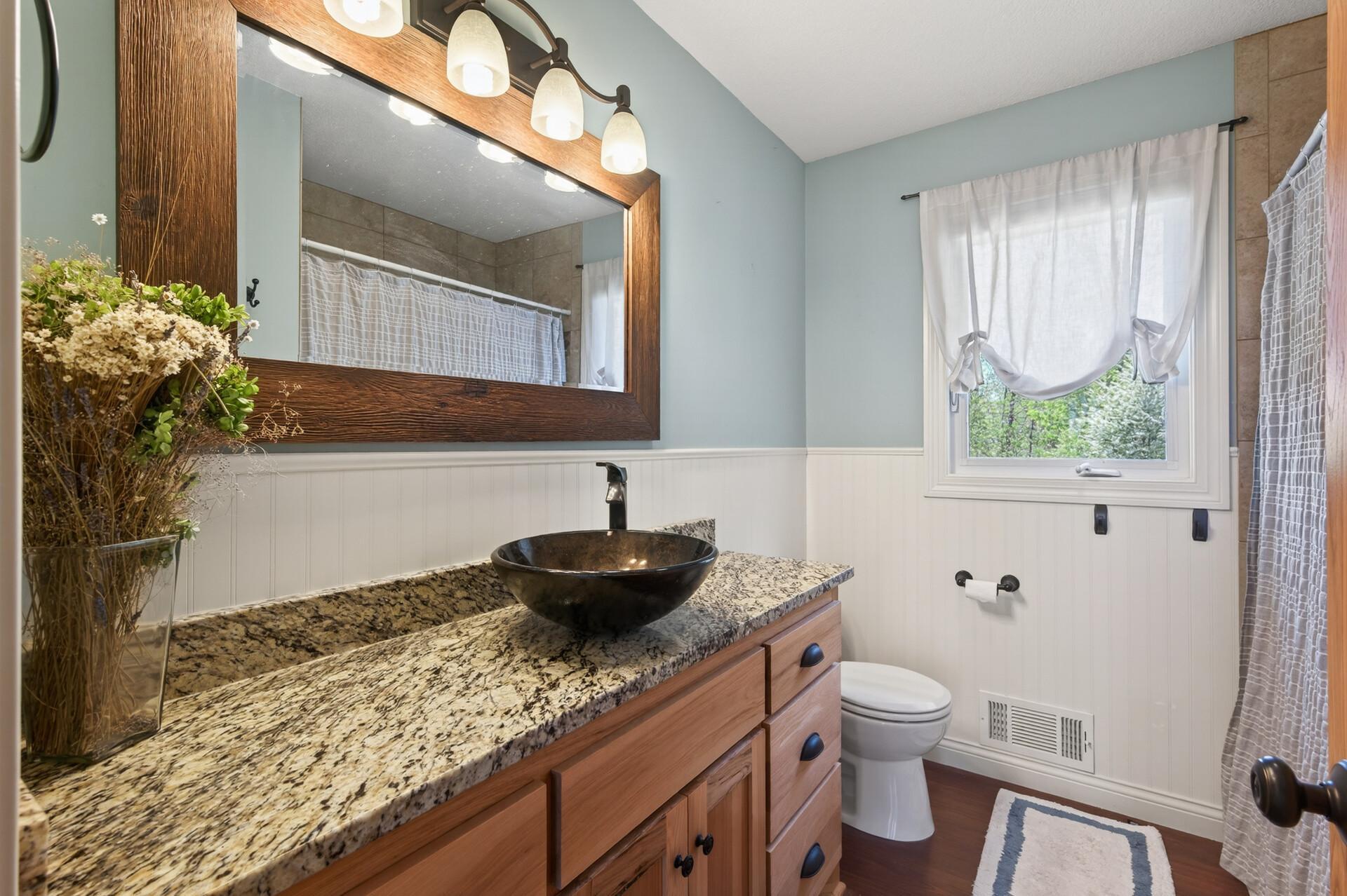 There is a full bathroom on the main level that serves the additional two bedrooms, updated with wainscotting, large vanity with granite top and vessel sink, framed mirror and neutral colors.