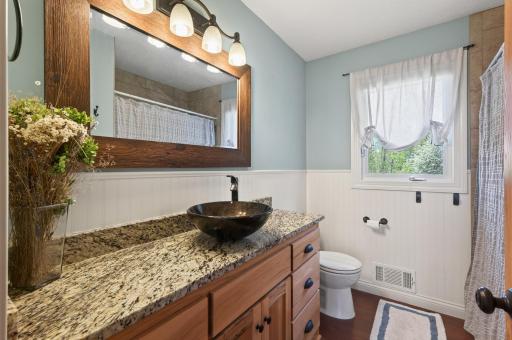 There is a full bathroom on the main level that serves the additional two bedrooms, updated with wainscotting, large vanity with granite top and vessel sink, framed mirror and neutral colors.