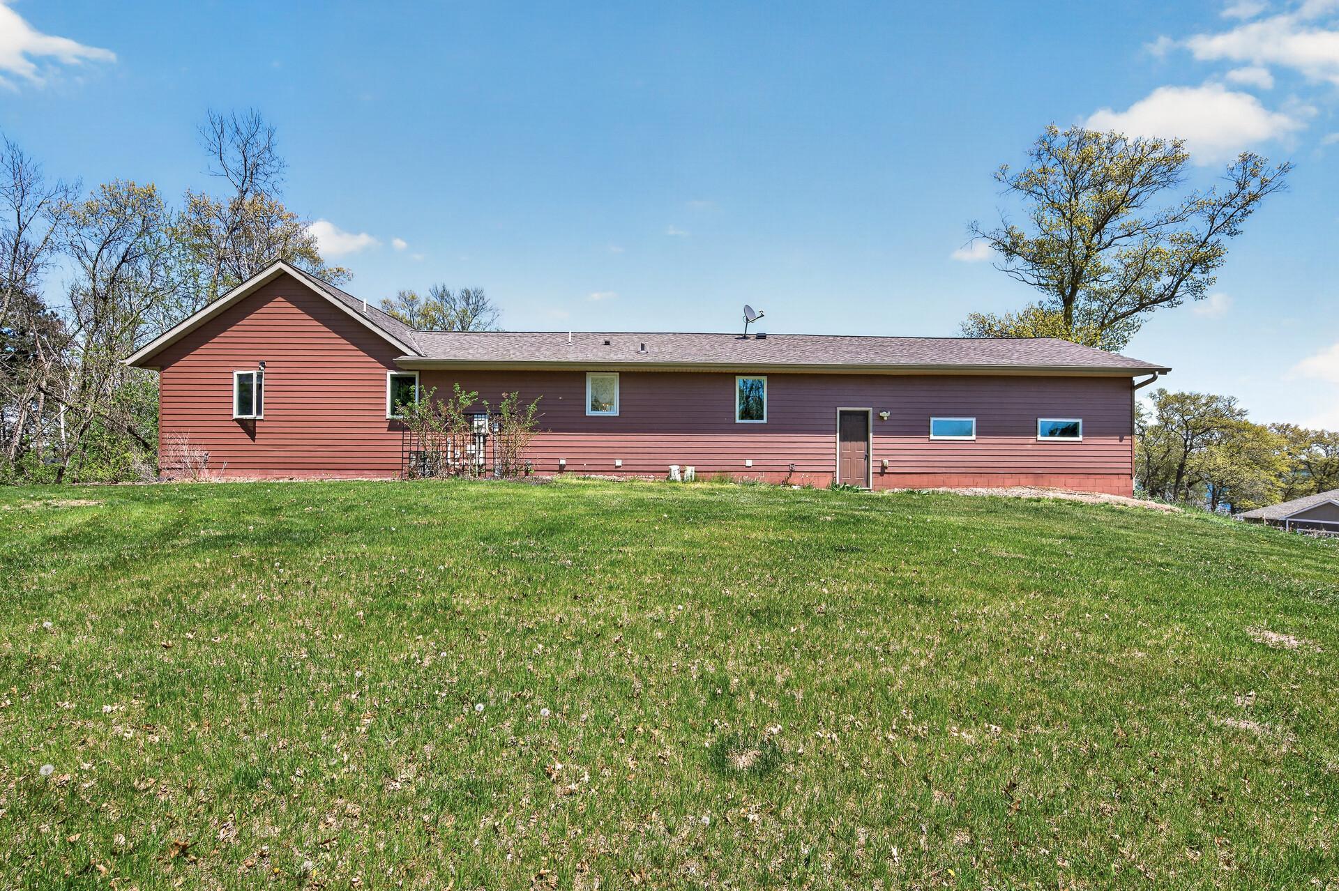 Rearview of the home, steel siding, access to the garage, large level yard.
