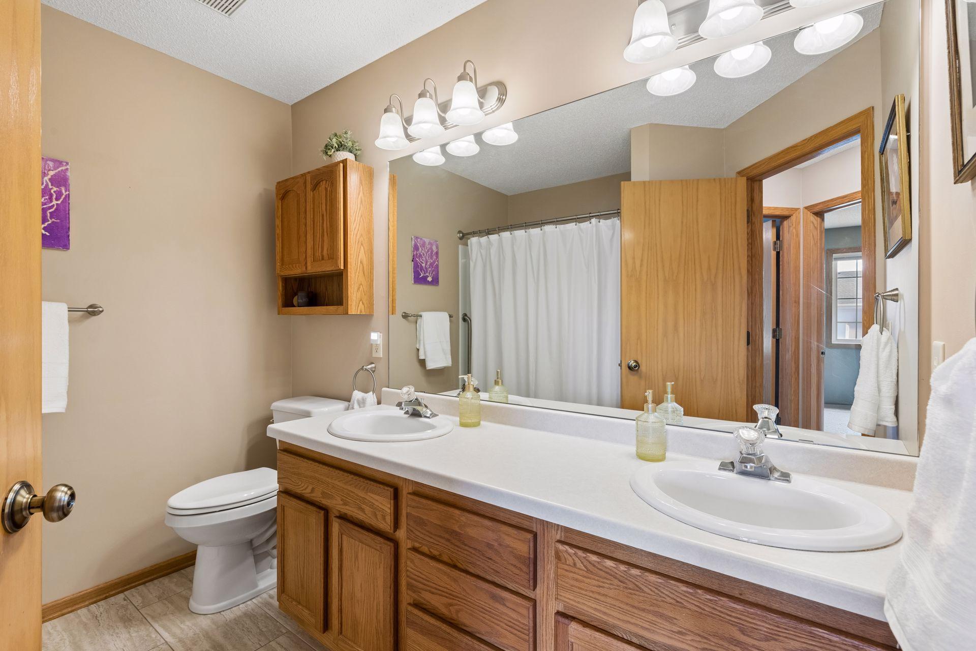 Full bath with double sinks, new flooring, toilets and bath surround