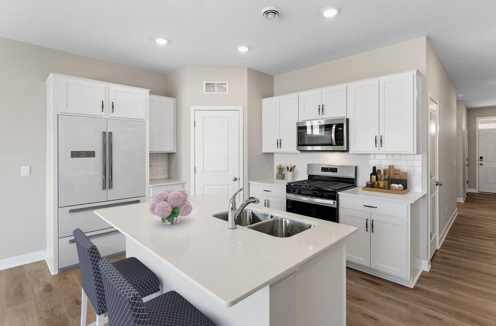 Modern kitchen with stainless steel appliances and microwave venting outside. Model home, finishes will vary.
