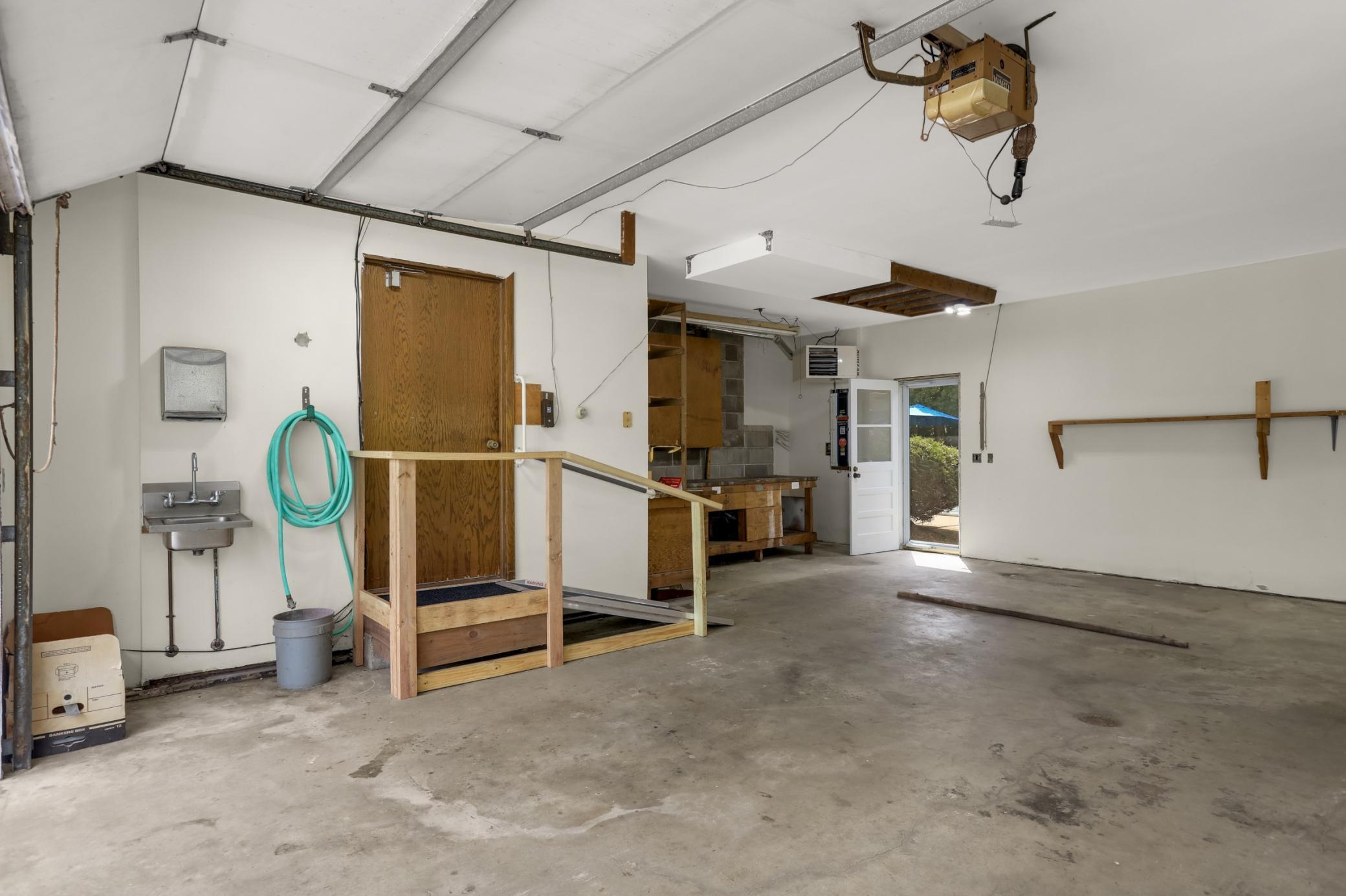 Oversized wide and deep 2 car garage with newer heater, workbench and sink! Over head storage area too!