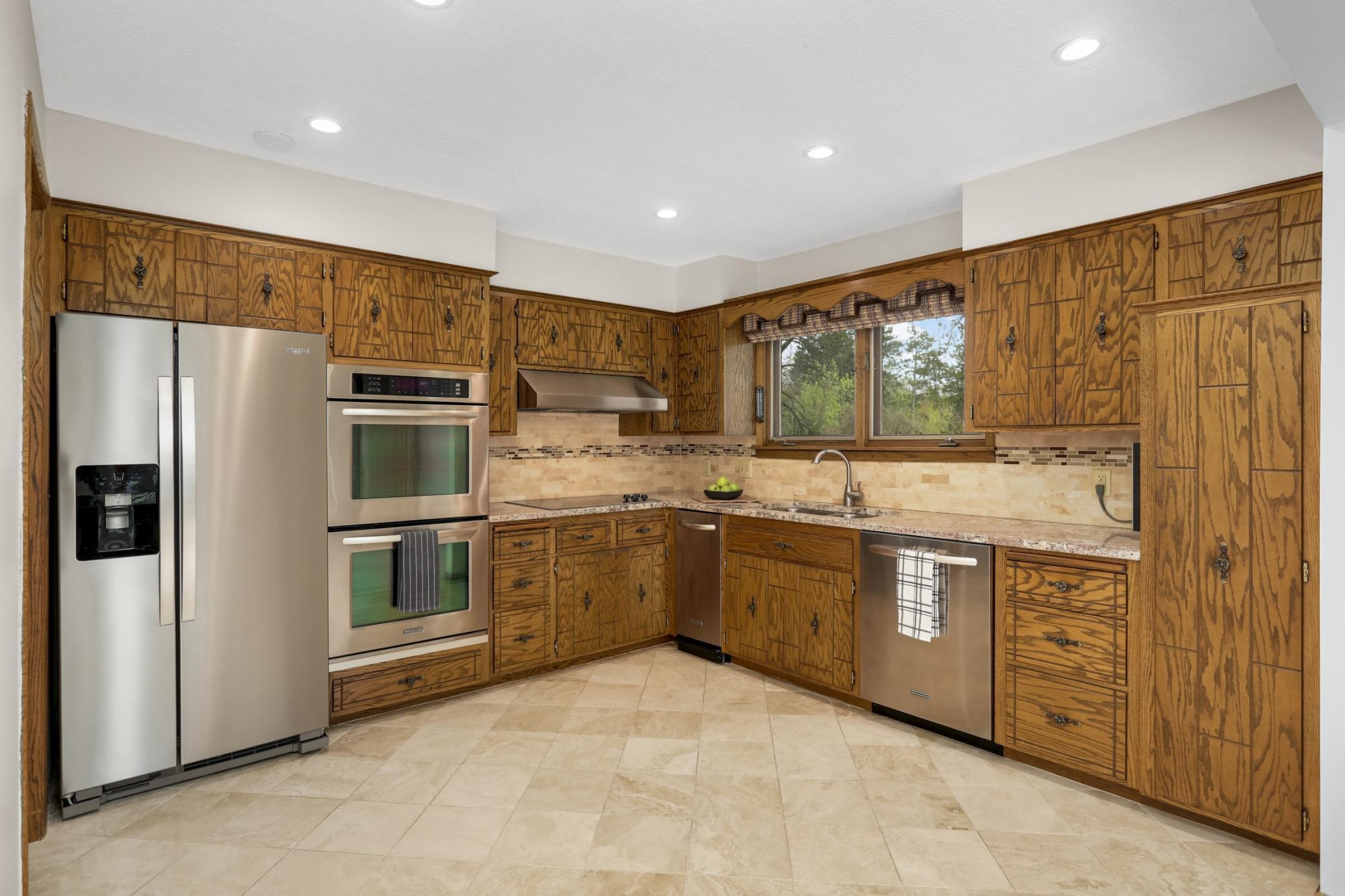 Newer stainless steel refrigerator, double oven, hood vent, microwave and trash compactor. Granit counters, title backsplash and flooring. Awesome kitchen views of pond & pool.