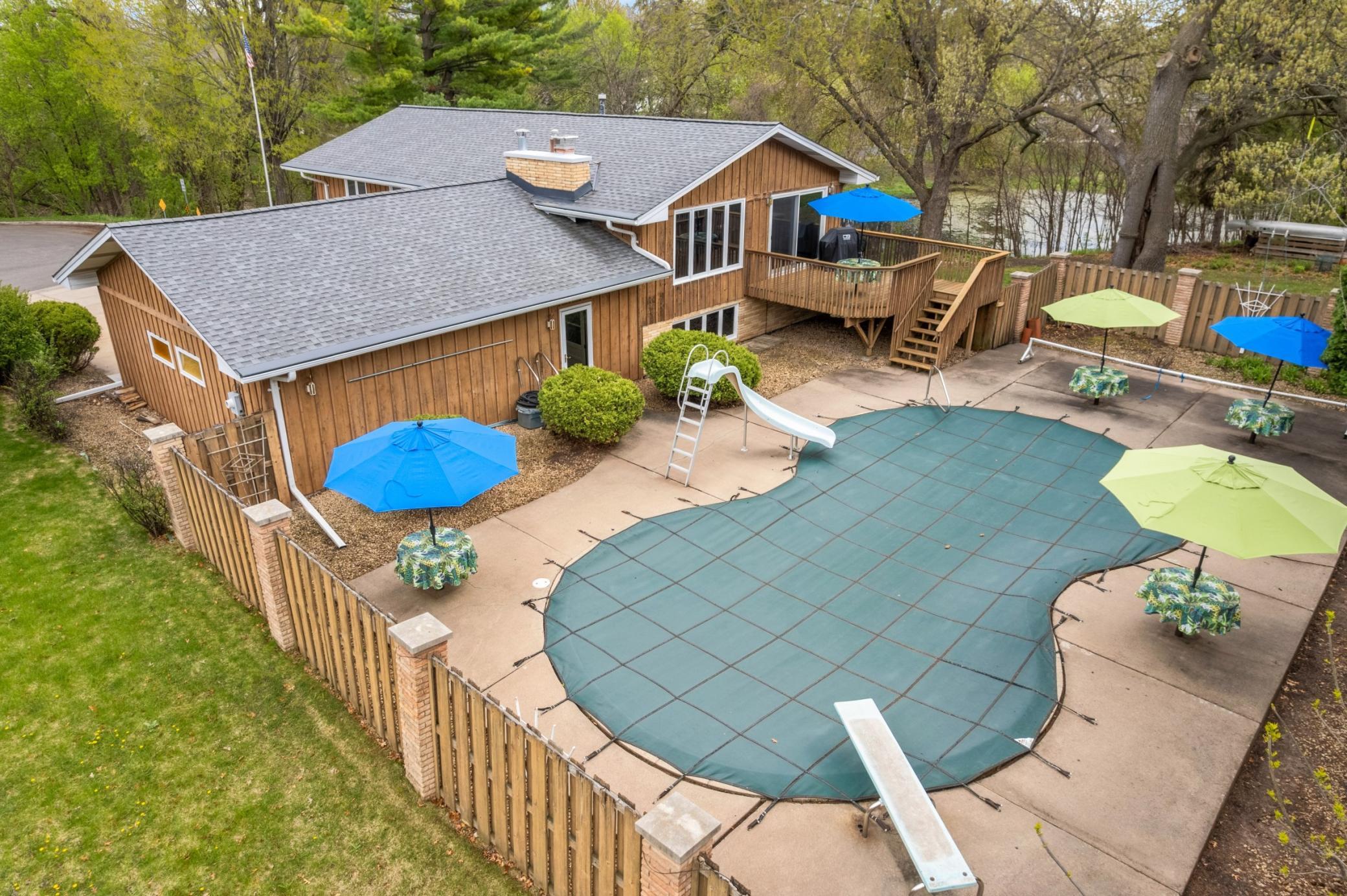 Large figure 8 shaped concrete pool with built in tables. Large oversized concrete decking. Slide, diving board and all pool equipment included! Cedar an brick privacy fence.