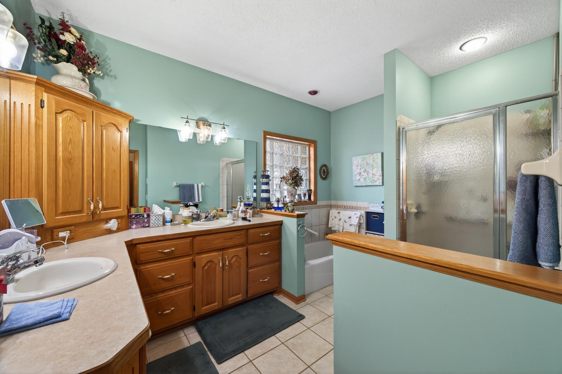 This full primary bathroom boasts dual vanities, abundant storage, and a separate tub and shower.