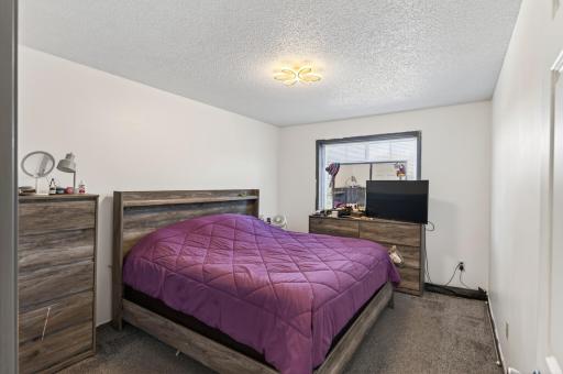First upper level bedroom features plush carpeting, neutral tones, and abundant natural light.