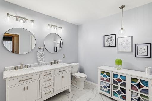 A furniture-style dual bowl vanity with marble countertops brings an air of elegance, while a walk-in shower featuring floor-to-ceiling marble with ornate tile insets delivers a spa-like experience youâll look forward to every day.