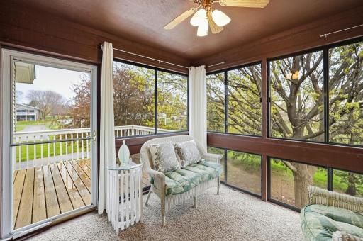 Floor-to-ceiling windows bathe the sun room in natural light while framing beautiful views of the backyard and green space beyond.