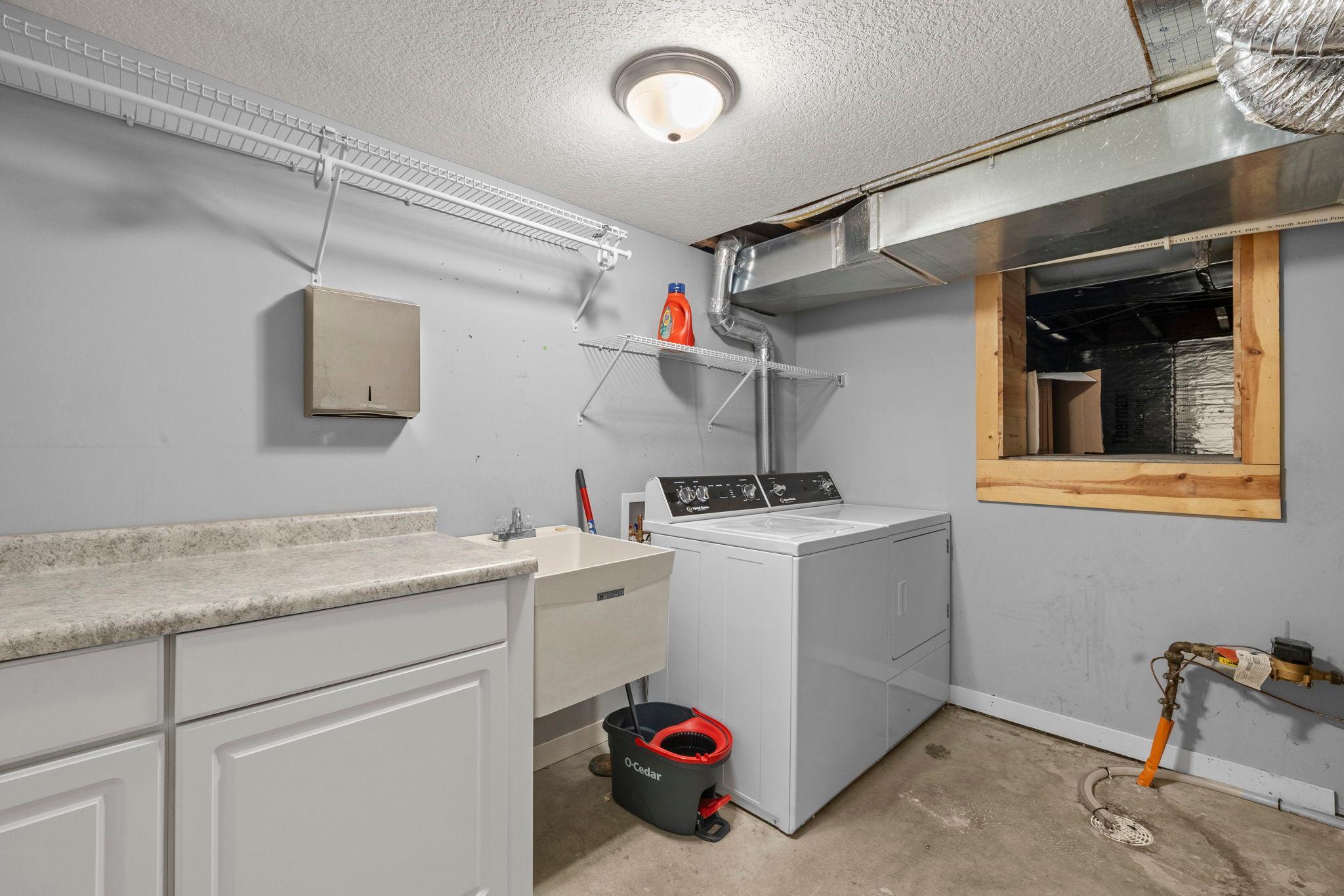 The laundry space is located on the lower level, featuring Speed Queen washer and dryer, cabinetry, counter space, and shelving with a nearby 47x11 crawl space that provides extensive additional storage.