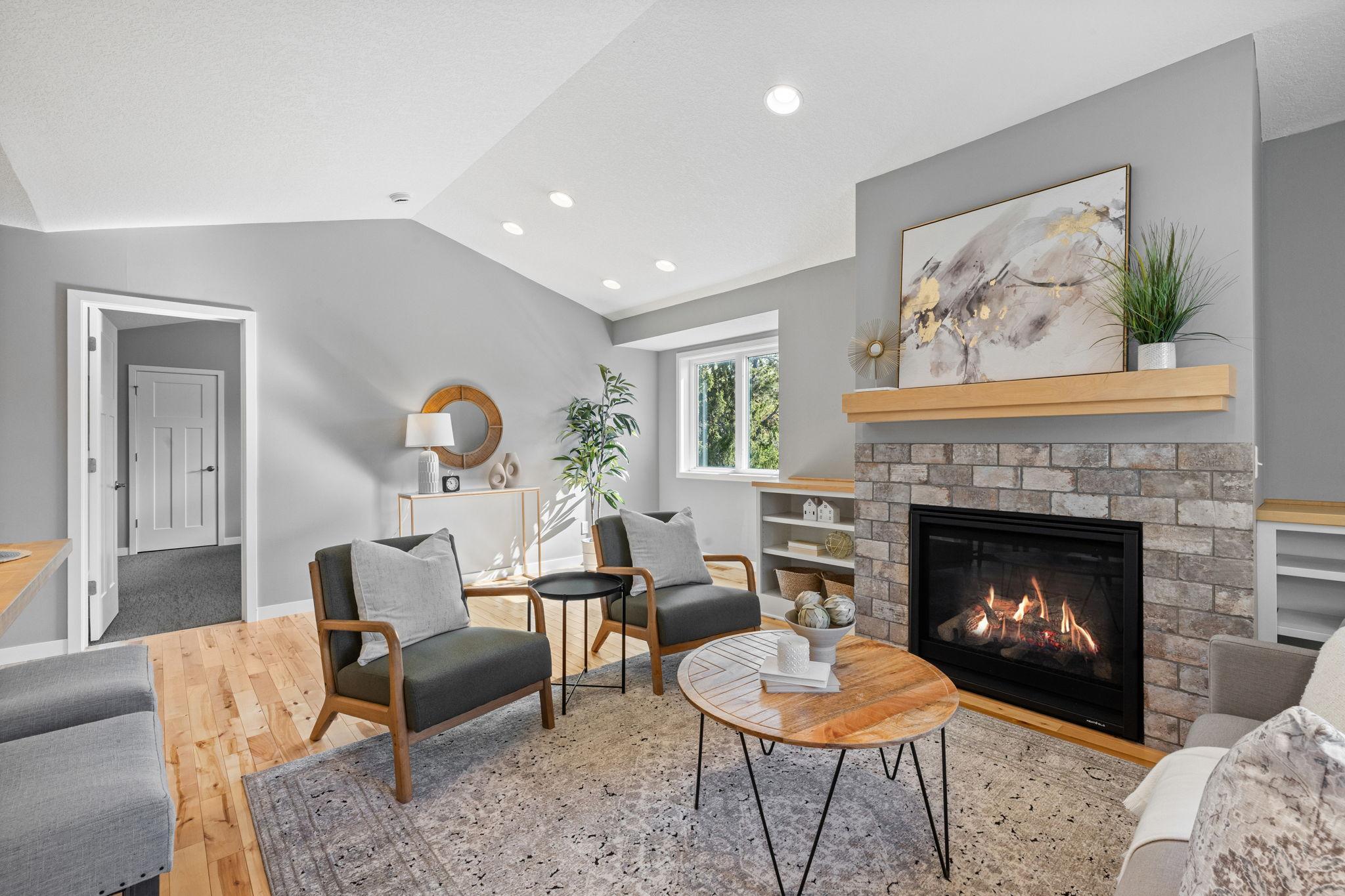 The connected living and dining area showcases a gas fireplace with stone surround and built-ins.