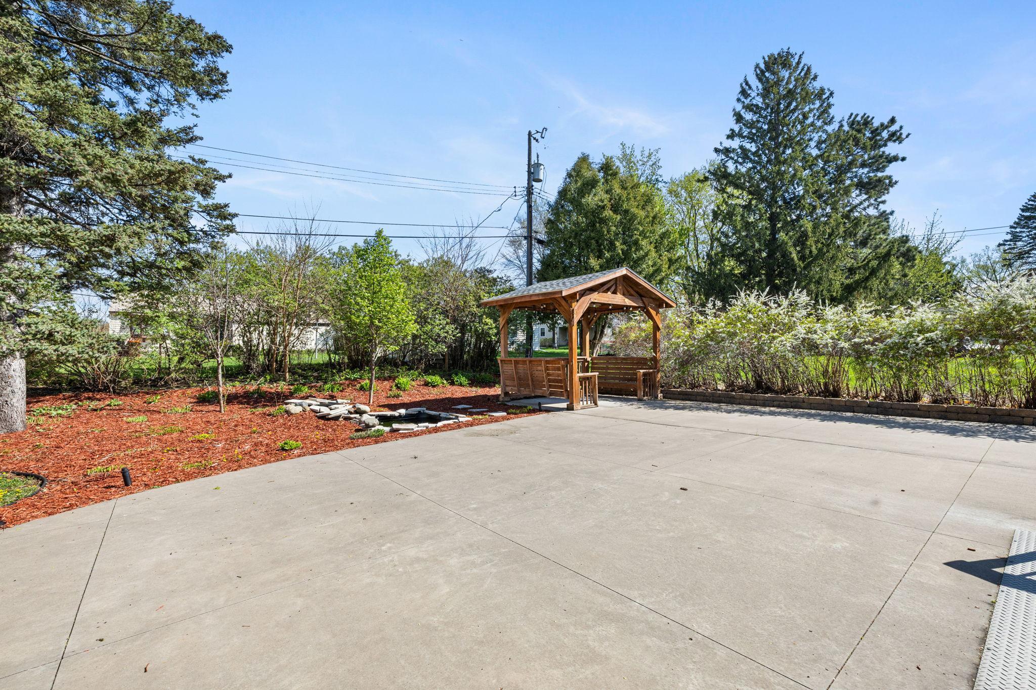 The patio is complemented by a nearby stone water feature and thoughtfully designed landscaping that enhances the home’s curb appeal.