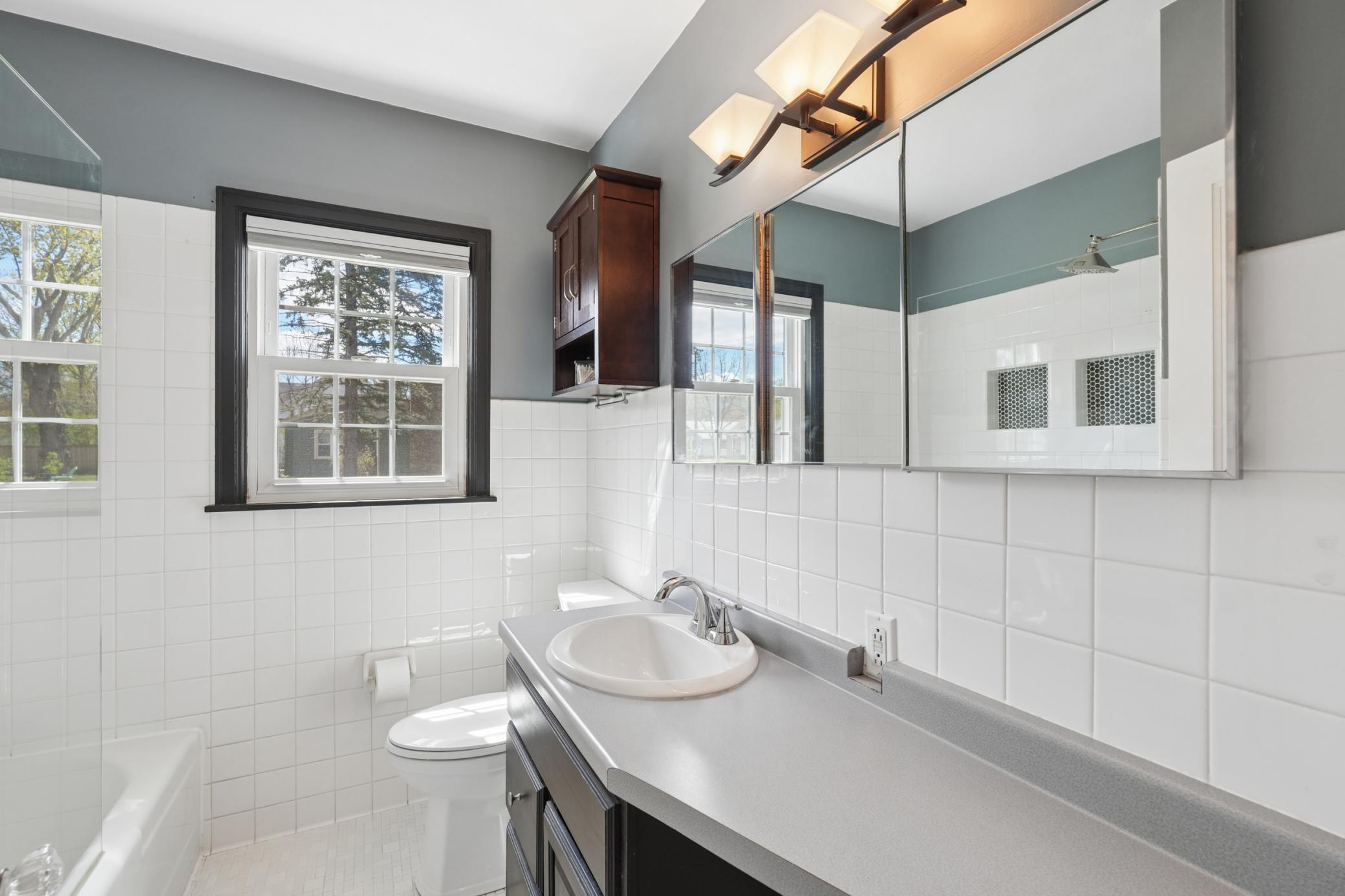 Full main floor bathroom with tiled floors and backsplash.