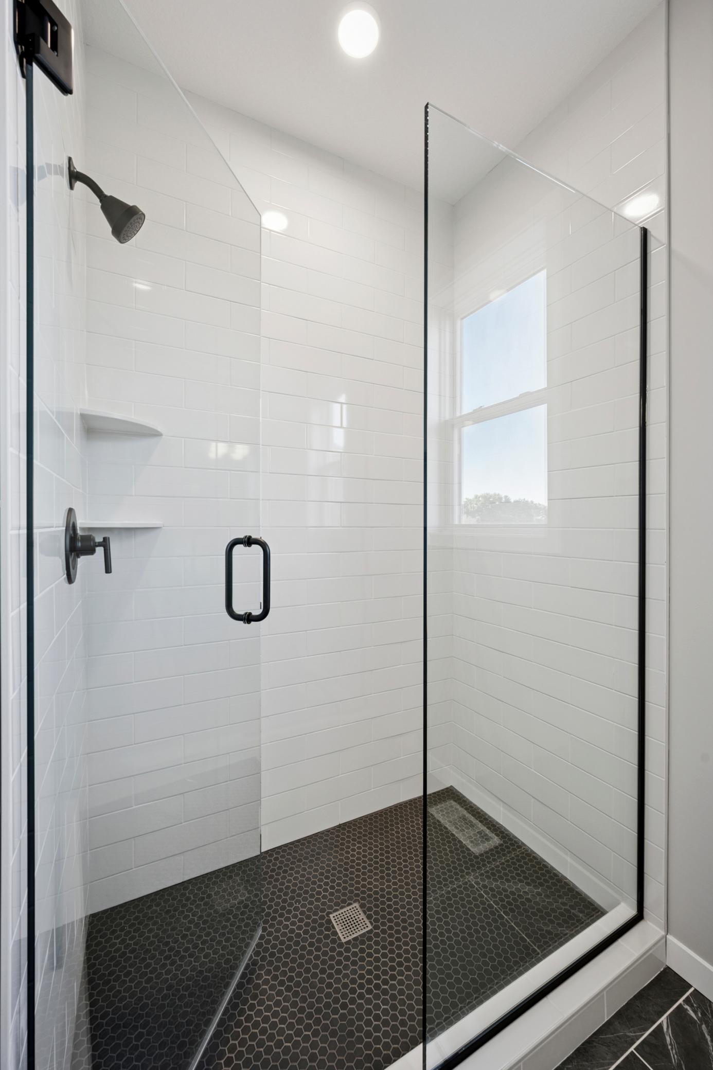 Lovely tiled shower to ceiling, and heavy glass shower door.