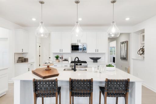 The kitchen features a fluid open-concept layout that is ideal for preparing meals, complemented by a multifunctional center island, plenty of cabinet space and quartz countertops.